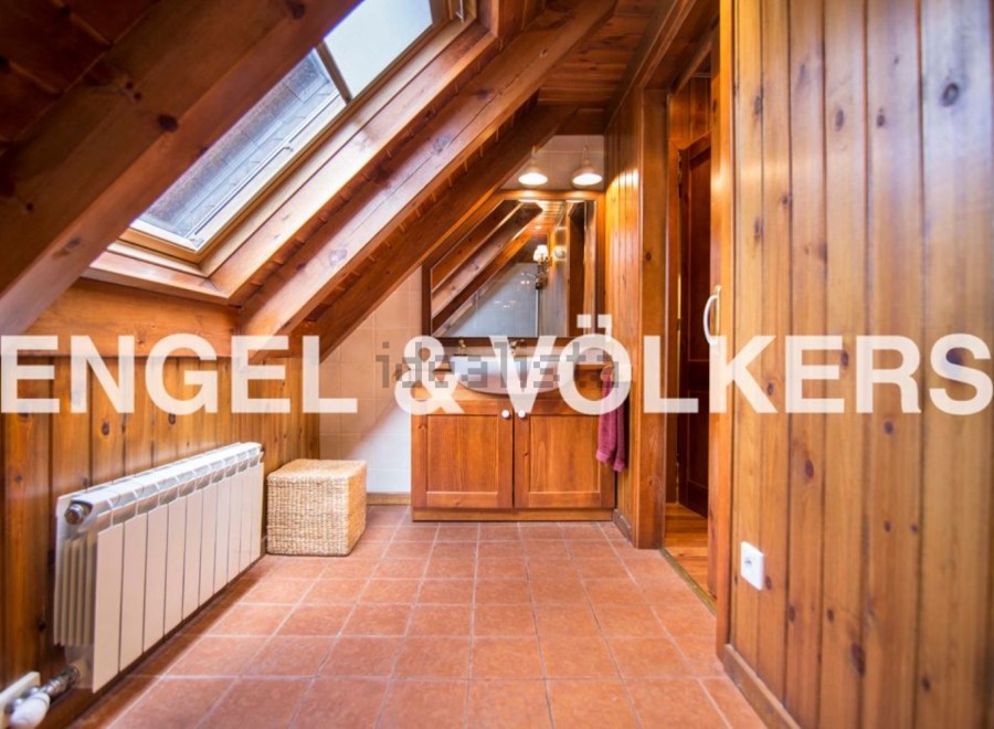 Charming attic bathroom with wooden beams, skylights, and terracotta tile flooring.