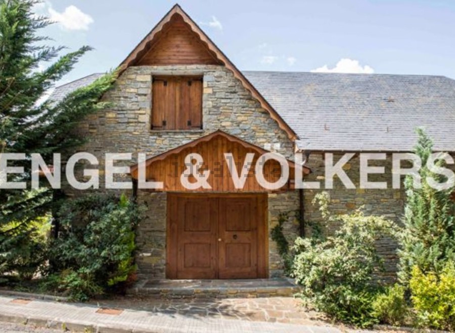 This charming stone house boasts a unique wooden facade and a spacious double door entrance.