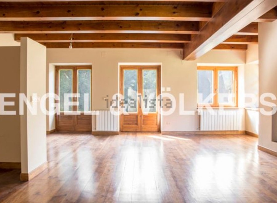 Spacious living area with hardwood floors and exposed wooden beams.