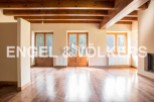 Spacious living area with hardwood floors and exposed wooden beams.