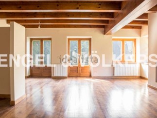 Spacious living area with hardwood floors and exposed wooden beams.
