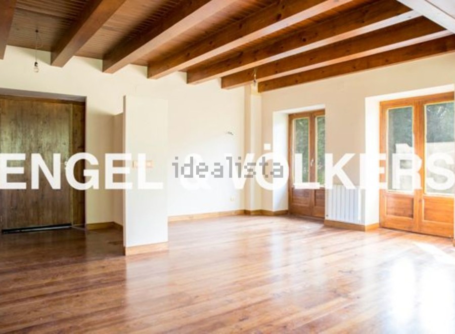 Spacious living area with hardwood floors and exposed wooden beams.