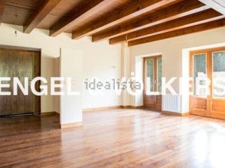 Spacious living area with hardwood floors and exposed wooden beams.