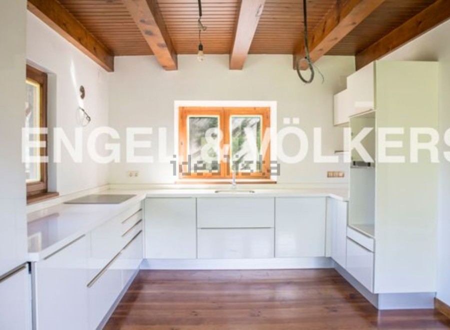 Modern kitchen with white cabinets and wooden beams.