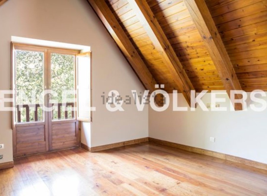 This attic bedroom boasts a charming wooden ceiling and large wooden doors that open to a scenic view.