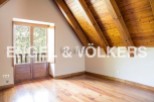 This attic bedroom boasts a charming wooden ceiling and large wooden doors that open to a scenic view.