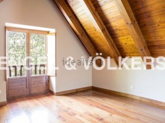 This attic bedroom boasts a charming wooden ceiling and large wooden doors that open to a scenic view.