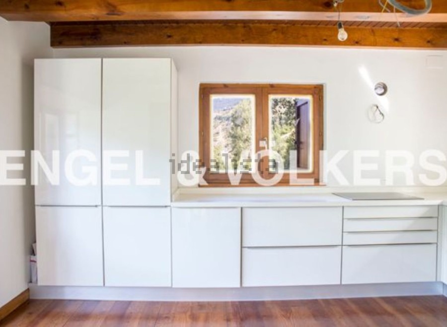 Modern kitchen with white cabinets and wooden beams.