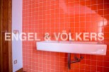 Modern bathroom with bright orange tiled walls and a sleek, white sink.