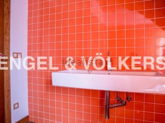 Modern bathroom with bright orange tiled walls and a sleek, white sink.