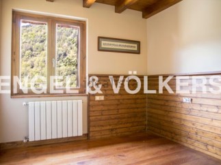 Cozy room with wooden wall paneling and large window offering scenic views.
