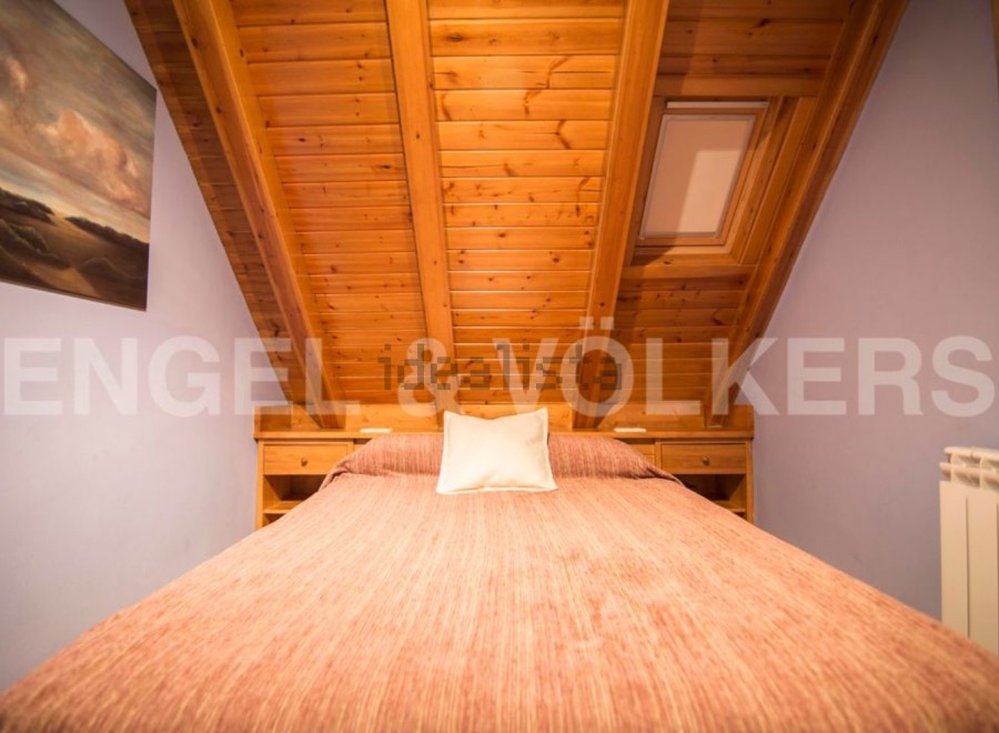 Cozy attic bedroom with wooden beams and skylight.