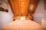 Cozy attic bedroom with wooden beams and skylight.