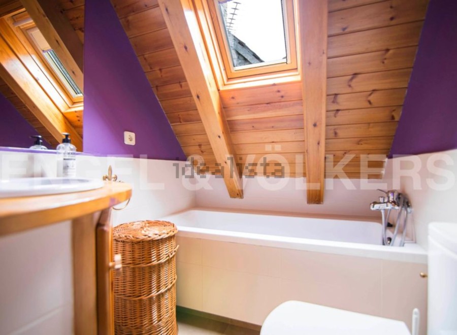 Charming attic bathroom with wooden beams, skylight, and purple walls.