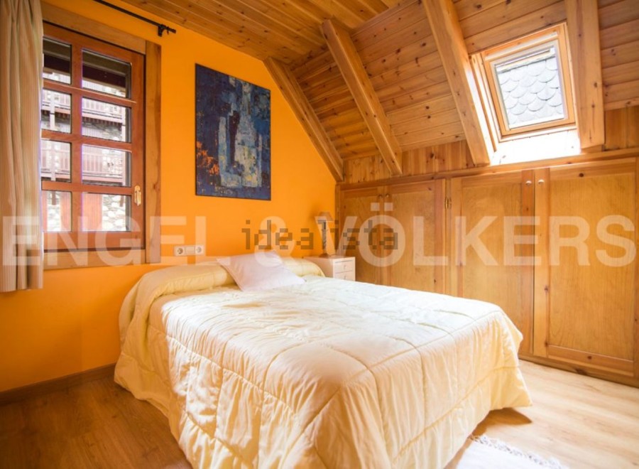 Cozy attic bedroom with wooden beams and built-in wardrobes.