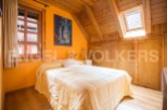 Cozy attic bedroom with wooden beams and built-in wardrobes.