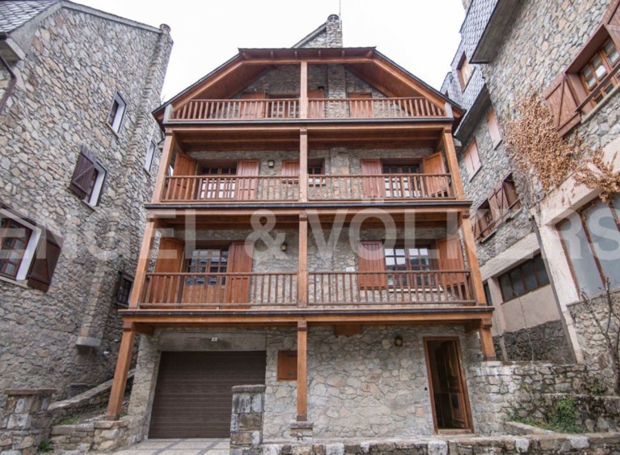 Charming stone house with wooden balconies and garage.