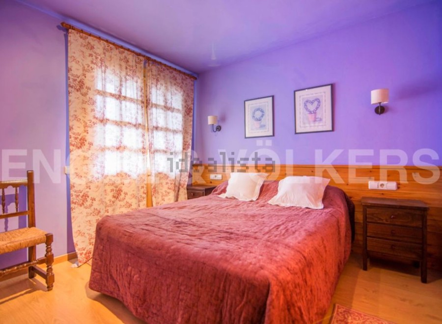 Charming bedroom with double bed, floral curtains, and wooden nightstand.