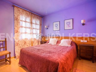 Charming bedroom with double bed, floral curtains, and wooden nightstand.