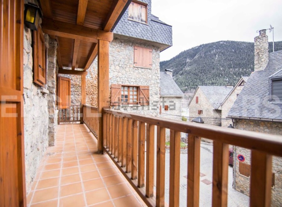 This stunning property boasts a charming wooden balcony overlooking a picturesque mountain village.