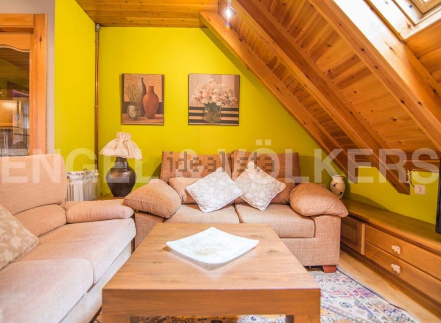 Cozy attic living space with wooden beams and bright yellow walls.
