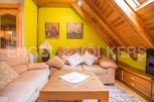 Cozy attic living space with wooden beams and bright yellow walls.