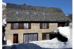 This charming stone house boasts a slate roof, large windows, and a rustic wooden door.