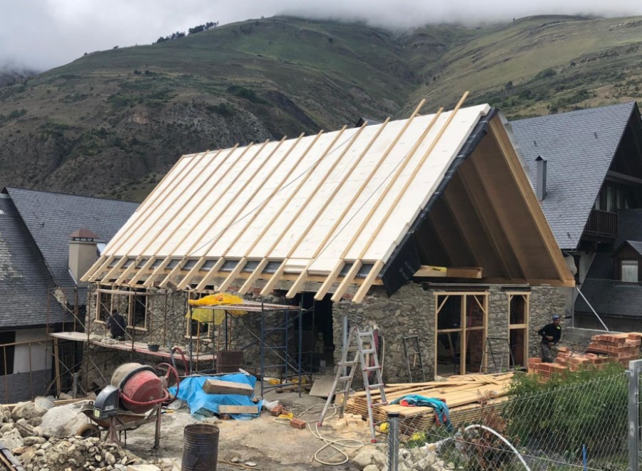 Mountainside home under construction boasts a unique A-frame design and stone exterior.