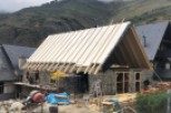 Mountainside home under construction boasts a unique A-frame design and stone exterior.