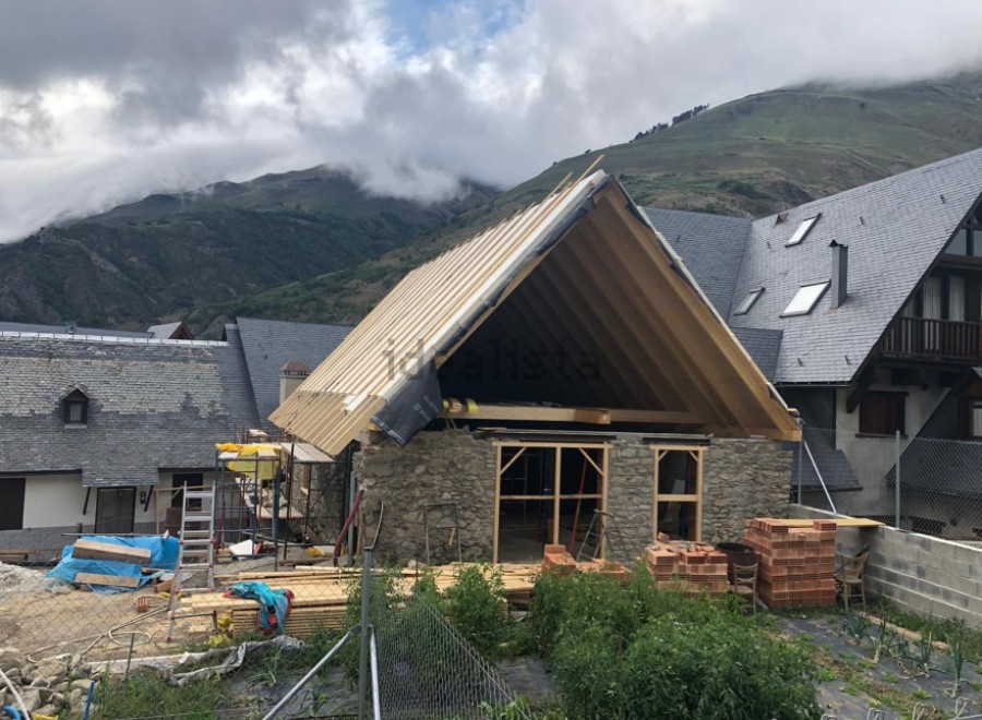 Mountain view home under construction with a unique stone and wood design.