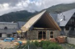 Mountain view home under construction with a unique stone and wood design.