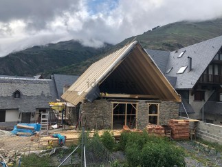 Mountain view home under construction with a unique stone and wood design.