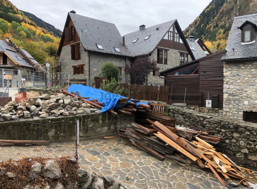 Mountainside stone house with slate roof, undergoing renovation.