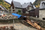 Mountainside stone house with slate roof, undergoing renovation.