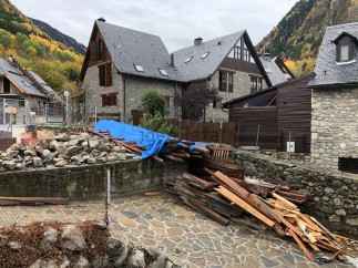 Mountainside stone house with slate roof, undergoing renovation.