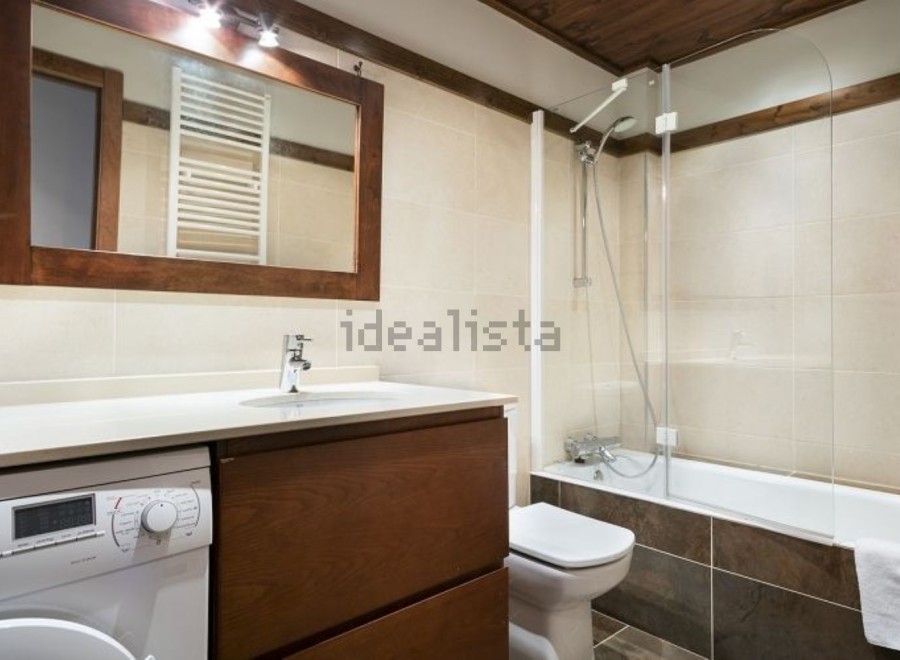 This stunning bathroom boasts a modern design with sleek wooden cabinetry and a spacious bathtub.