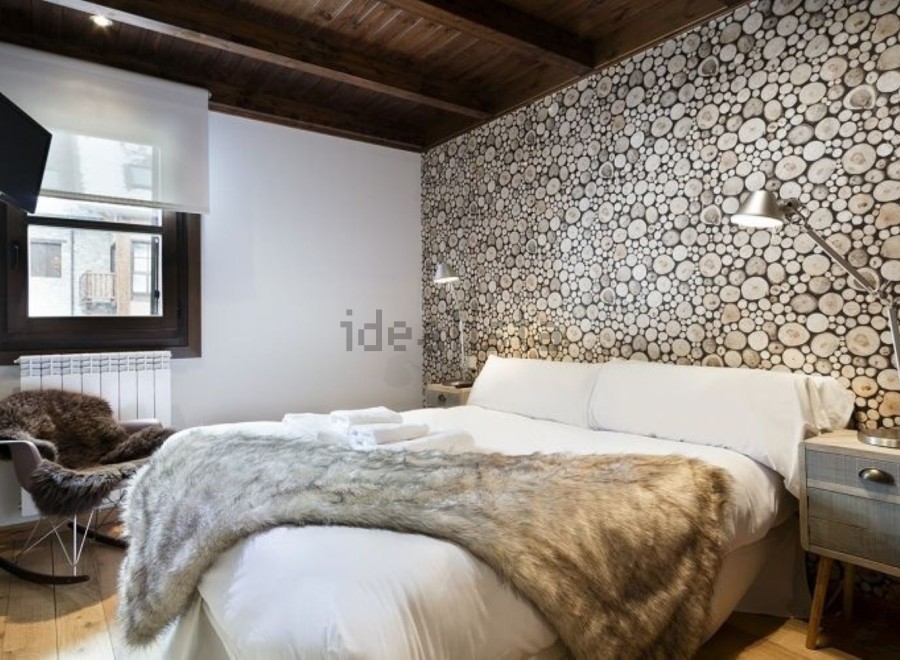 Cozy cabin bedroom with wood slice accent wall, plush fur throw, and comfortable rocking chair.