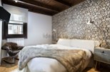 Cozy cabin bedroom with wood slice accent wall, plush fur throw, and comfortable rocking chair.