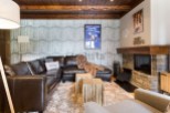 Cozy mountain chalet with leather sectional sofa, stone fireplace, and wood-paneled ceiling.