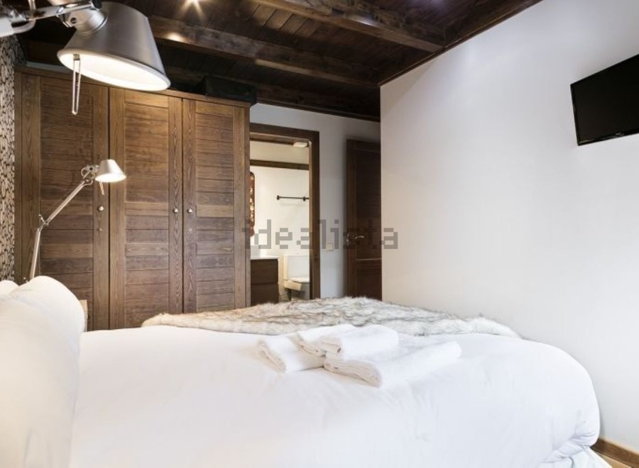 Cozy bedroom with wooden wardrobe and white bedding.