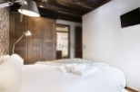 Cozy bedroom with wooden wardrobe and white bedding.