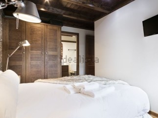 Cozy bedroom with wooden wardrobe and white bedding.