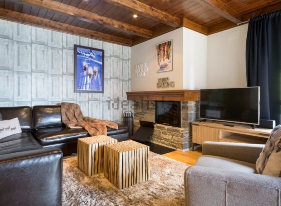 Cozy living room with a leather sectional sofa, a stone fireplace, and a large flat-screen TV.