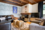 Cozy living room with a leather sectional sofa, a stone fireplace, and a large flat-screen TV.