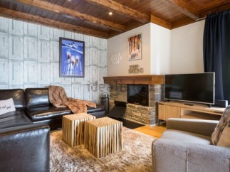 Cozy living room with a leather sectional sofa, a stone fireplace, and a large flat-screen TV.
