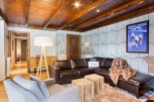 This stunning chalet boasts a spacious living area with a cozy leather sectional sofa, perfect for relaxing after a day on the slopes.