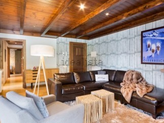 This stunning chalet boasts a spacious living area with a cozy leather sectional sofa, perfect for relaxing after a day on the slopes.