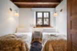 Cozy twin bedroom with rustic wooden beams and a charming window overlooking the town.