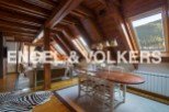 This stunning attic apartment boasts a spacious open-plan living area with exposed wooden beams and large skylights, creating a bright and airy atmosphere.