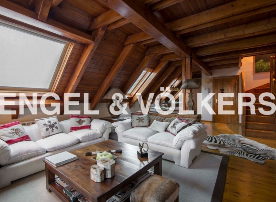 This stunning attic apartment boasts a spacious living area with exposed wooden beams and skylights, creating a bright and airy atmosphere.